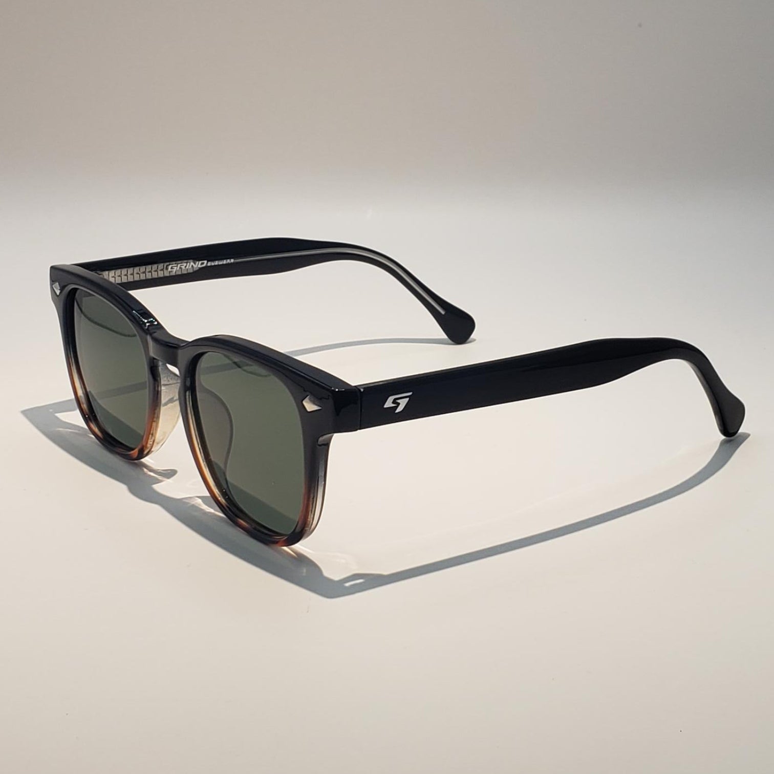 Sunglasses with black frames and dark lenses on a light gray background