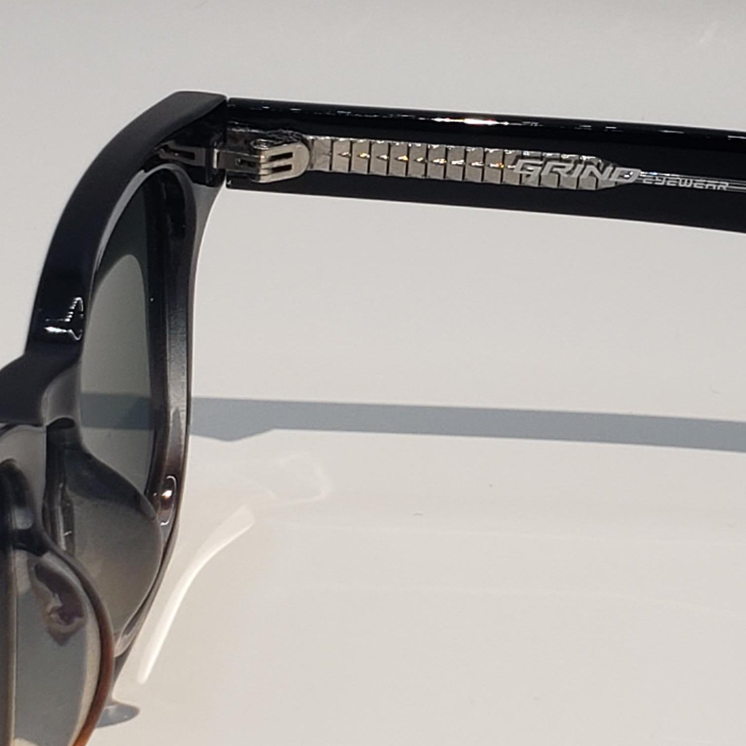 Black sunglasses with a reflective surface on a light gray background