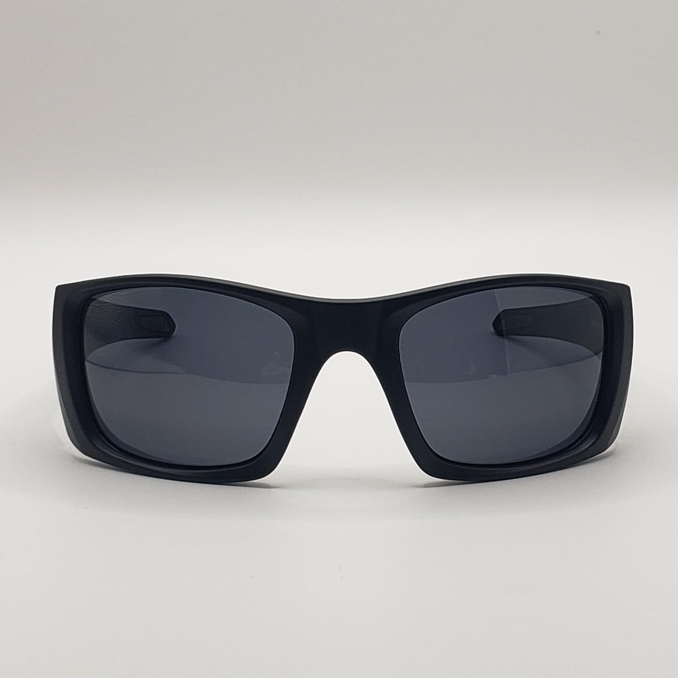 Black sunglasses with dark lenses on a light gray background