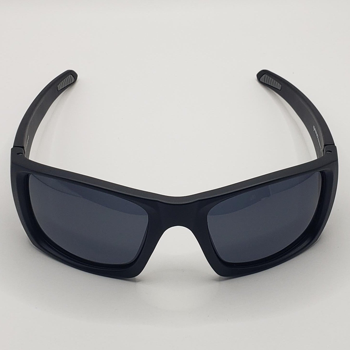 Black sunglasses with dark lenses on a light gray background