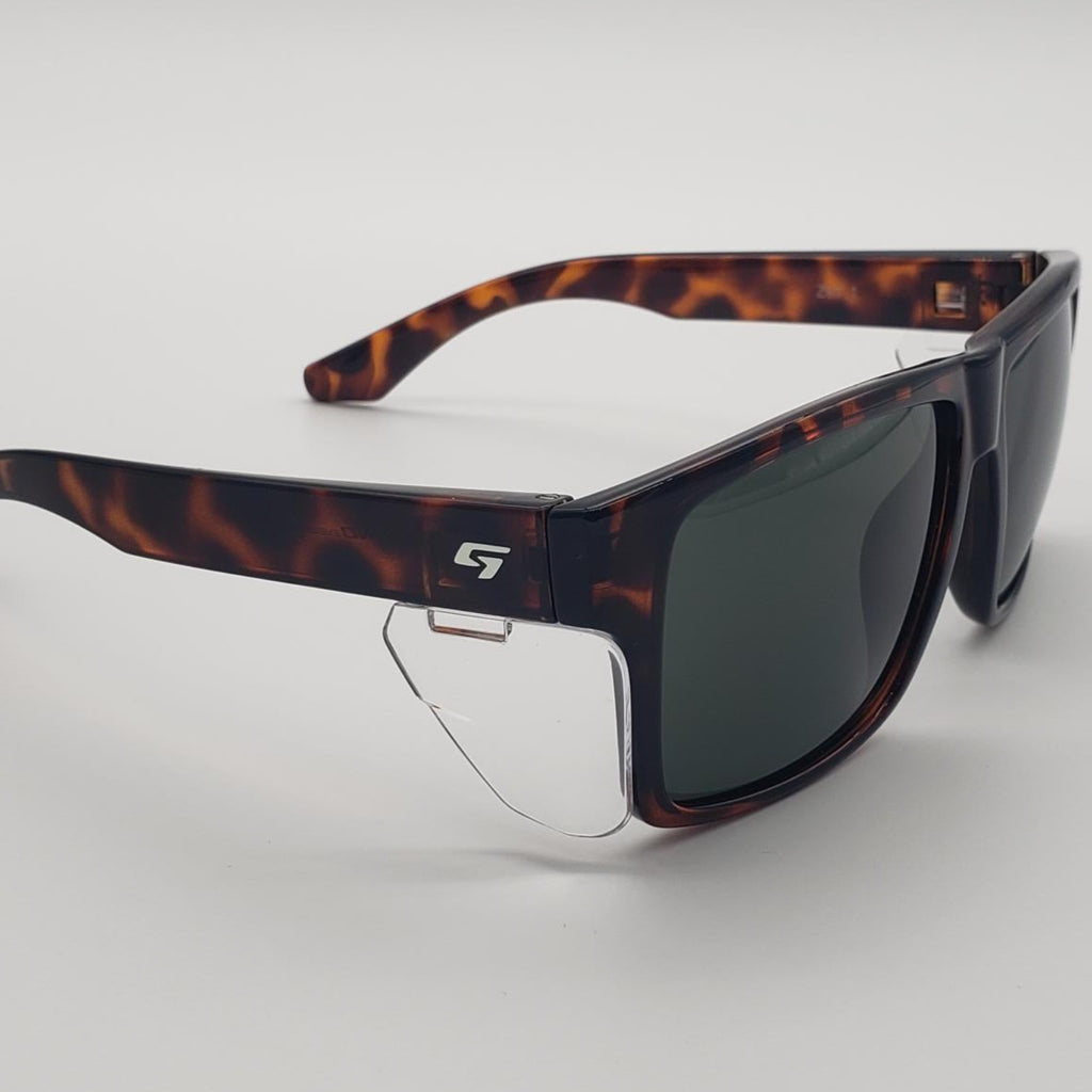 A pair of wraparound sunglasses with a dark brown and black tortoiseshell patterned frame and dark tinted lenses, shown on a neutral light gray background.