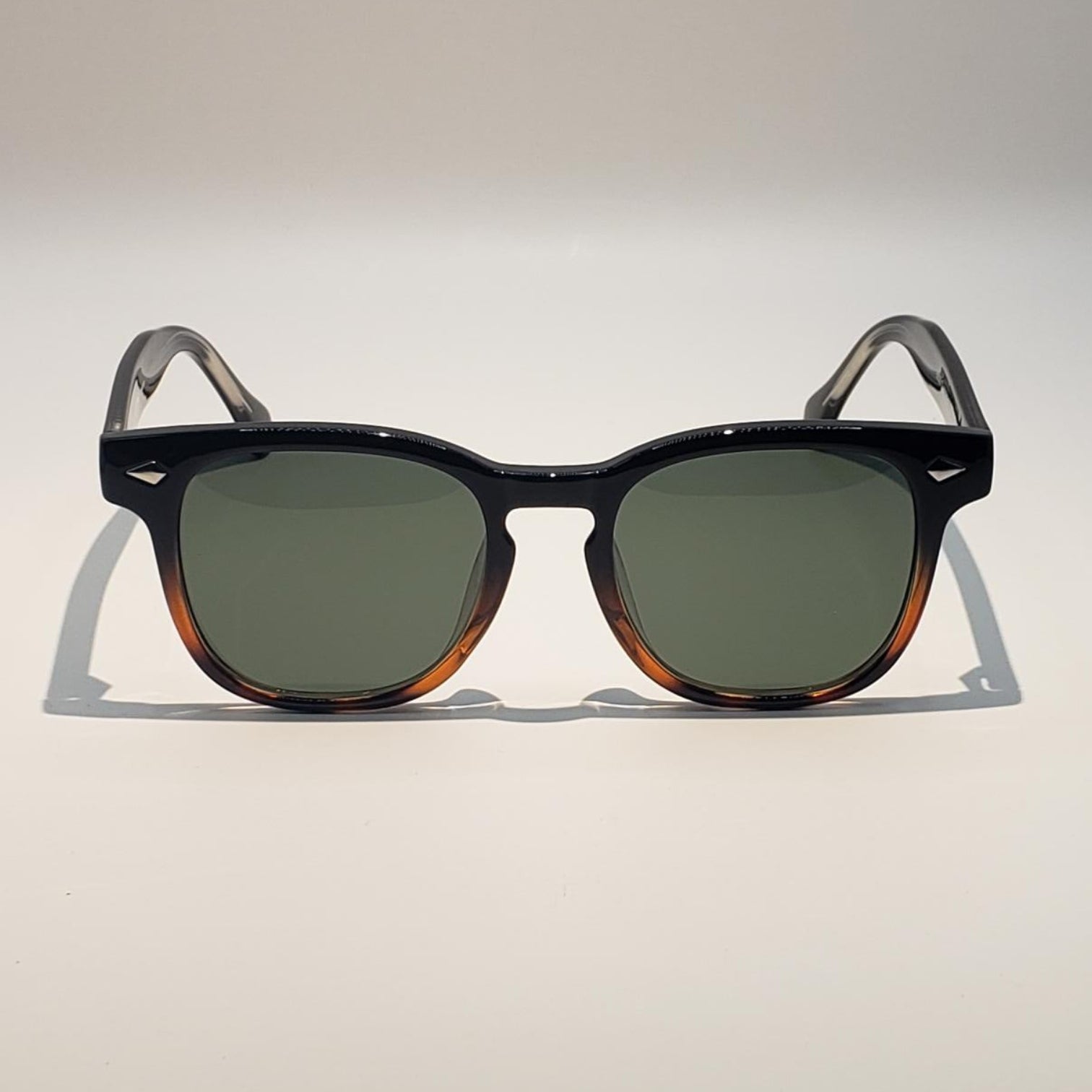 Sunglasses with tortoiseshell frame and green lenses on a white background